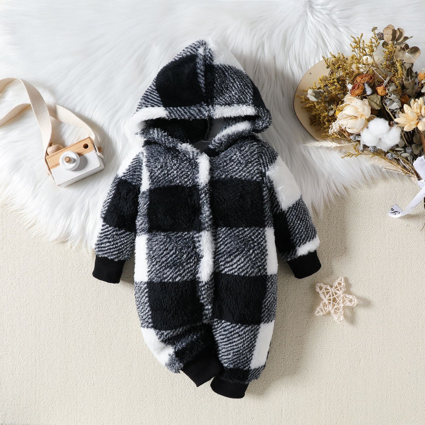 Black and white checkered baby onesie with a hood on a light background
