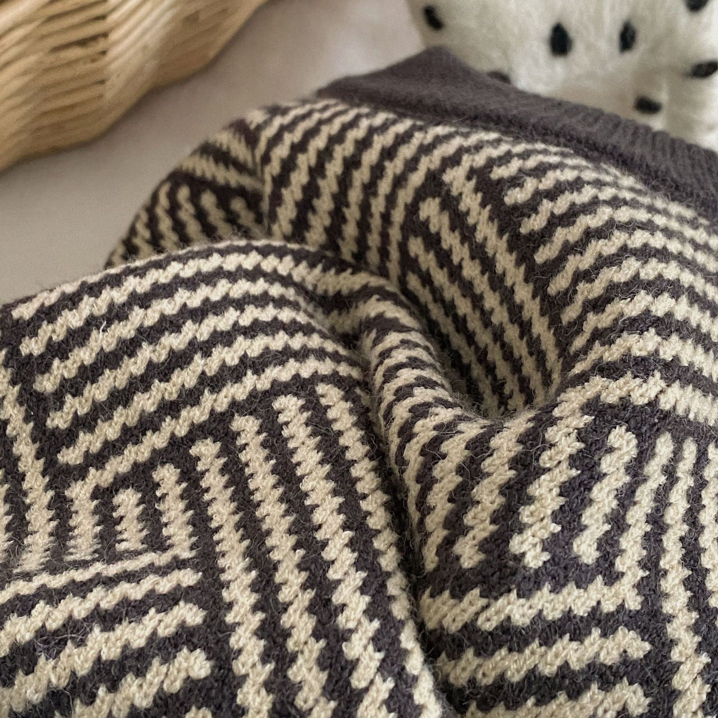 Close-up of a textured blanket with a geometric pattern on a neutral background
