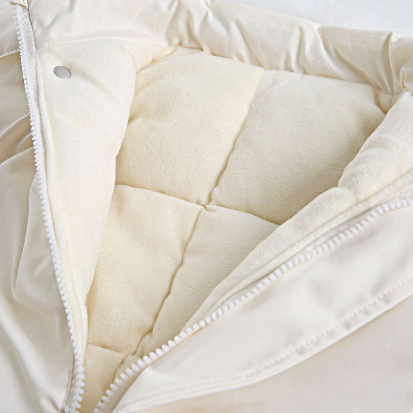 Close-up of a beige quilted jacket lining with a zipper.