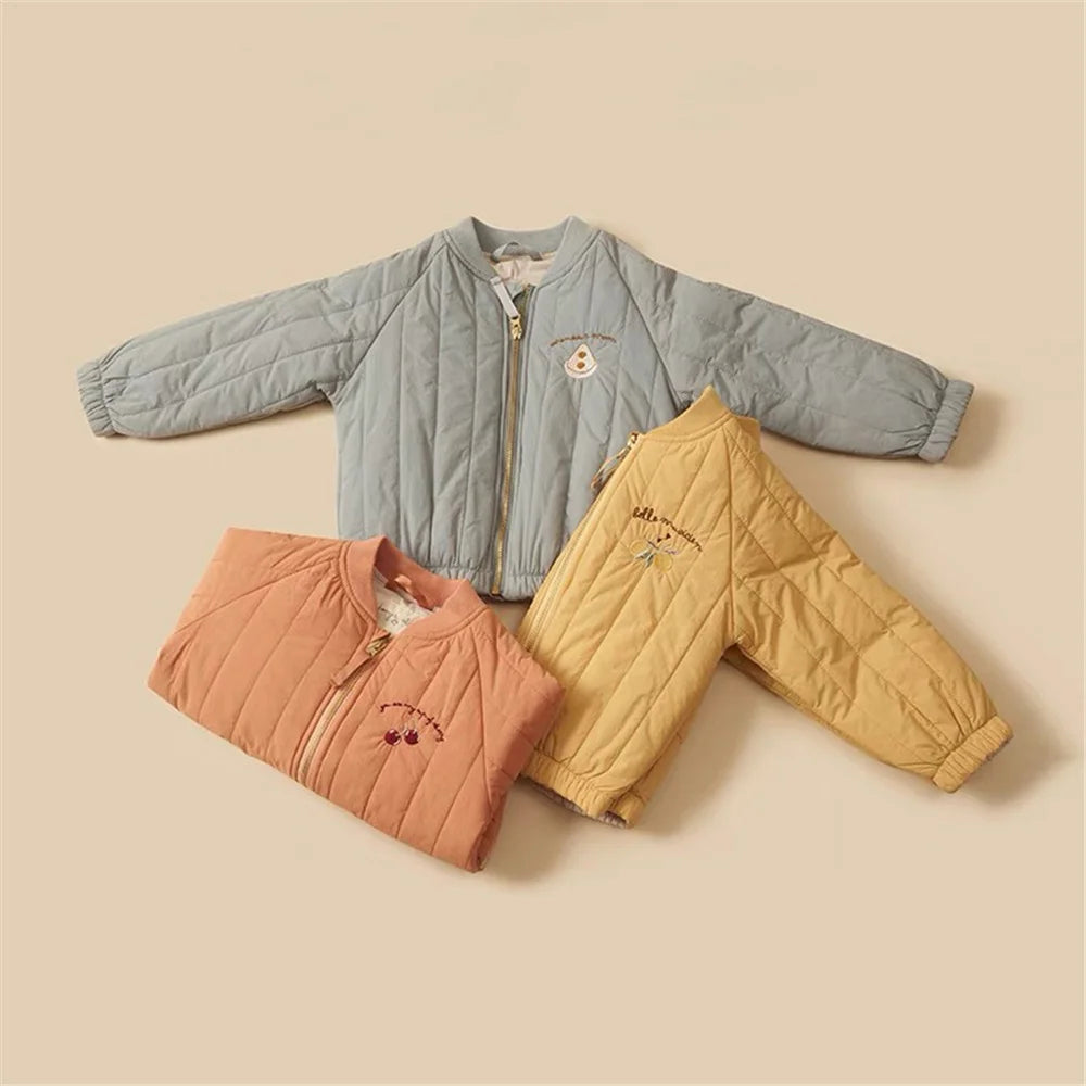Three children's quilted jackets in blue, orange, and yellow on a beige background