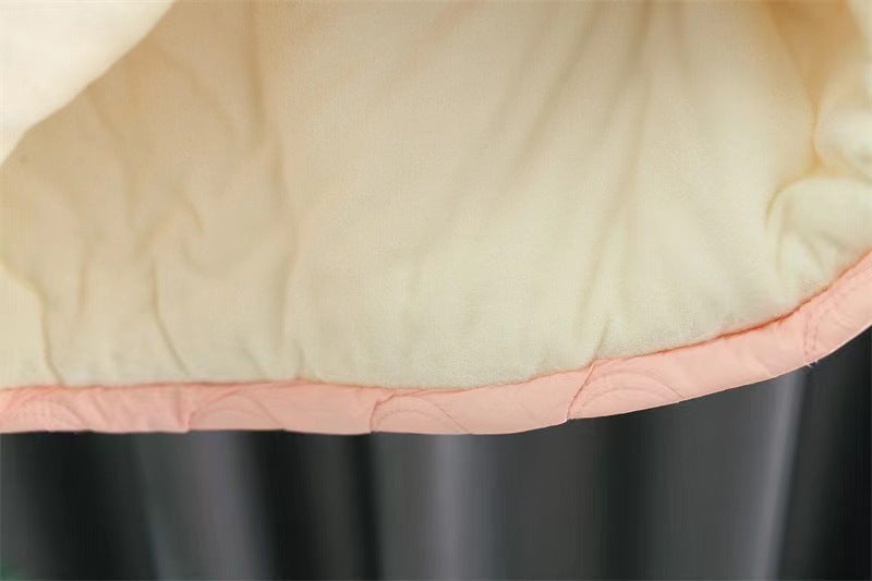 Close-up of a quilted fabric with a pink border on a dark background