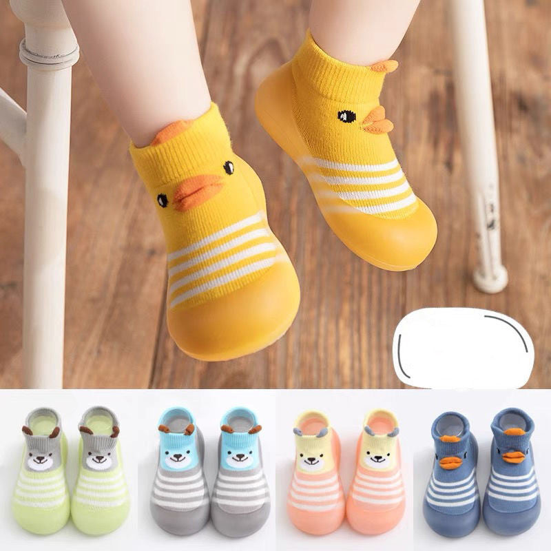 Yellow duck-themed socks with a close-up of feet wearing them on a wooden floor.