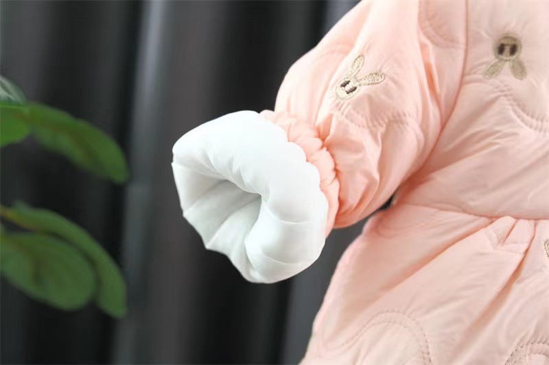 Close-up of a pink quilted jacket with white cuffs against a dark background