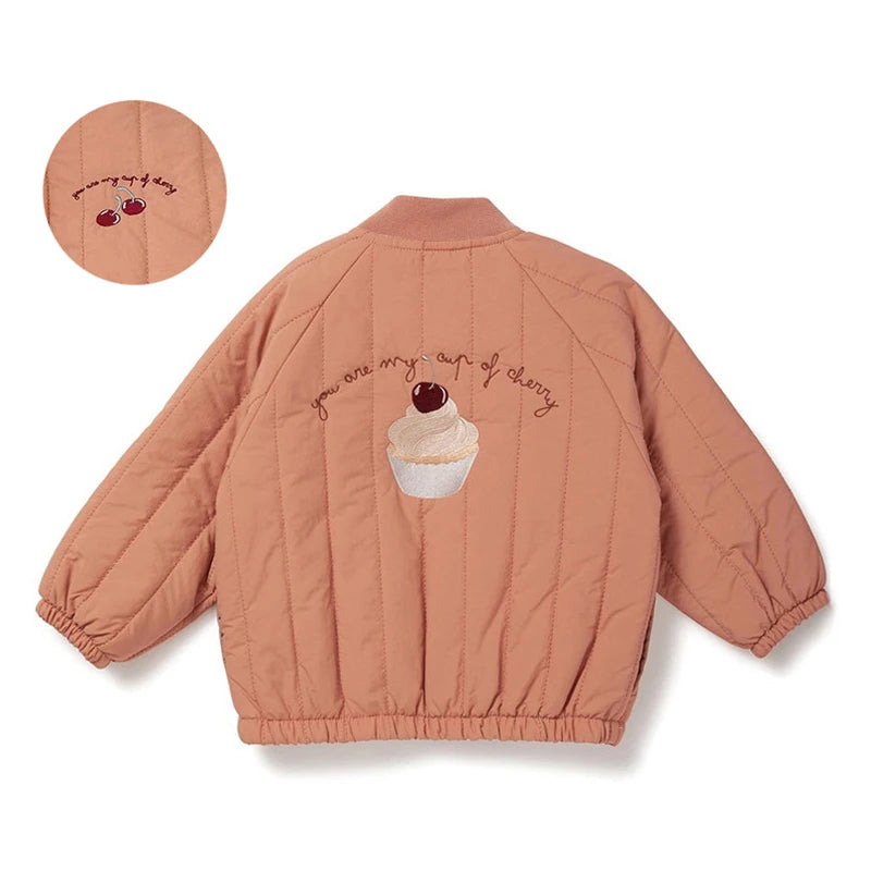 Peach-colored quilted jacket with cupcake and cherry design on a white background