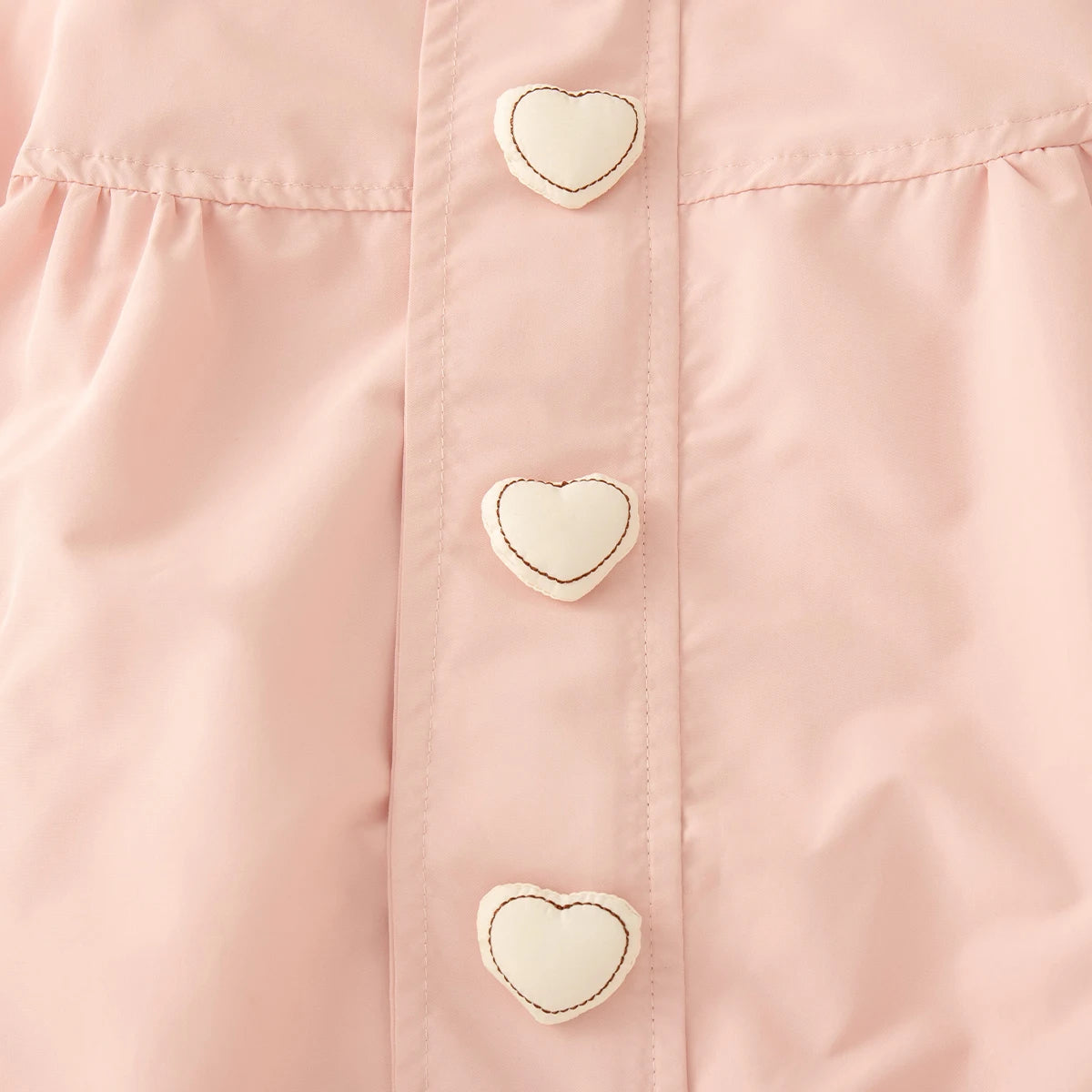 Close-up of a pink shirt with heart-shaped buttons.