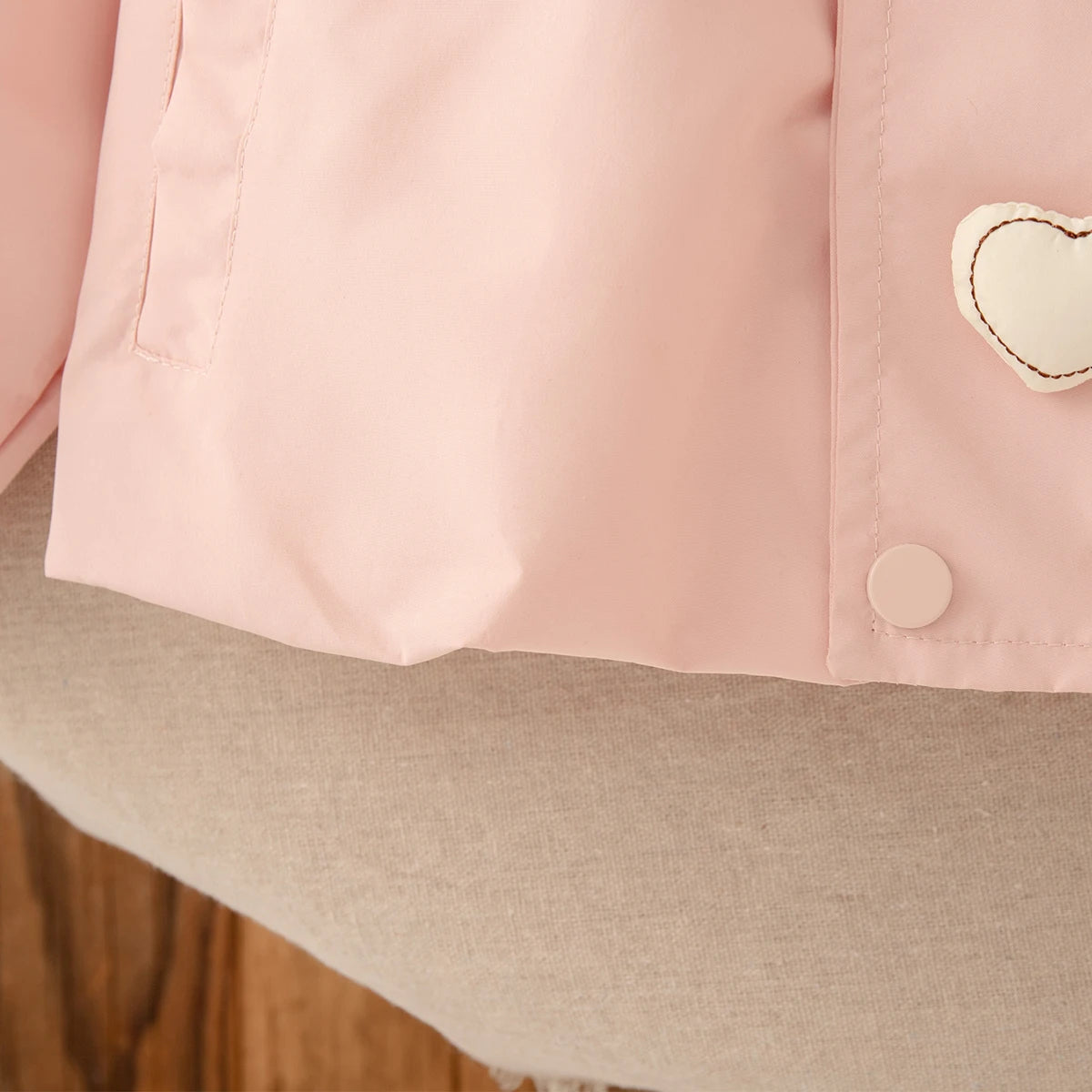 Close-up of a pink garment with a heart-shaped patch on a neutral background