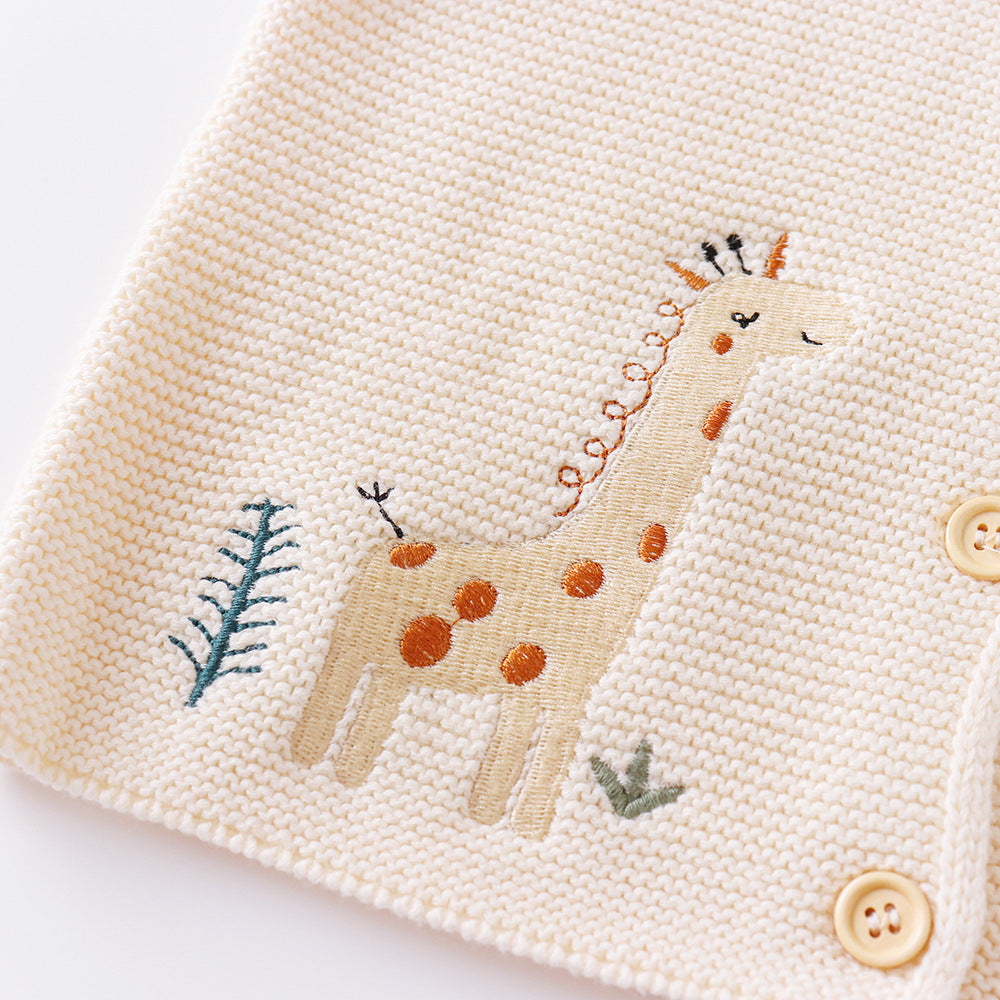 Embroidered giraffe design on a fabric surface with buttons.