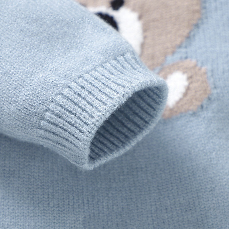 Close-up of a blue knitted sweater with a bear design on a light blue background