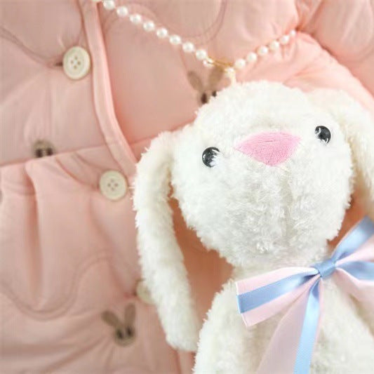 White plush bunny with a pink bow on a pink textured background