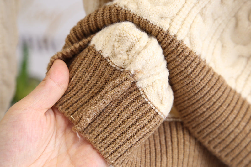 Close-up of a hand holding a brown and beige knitted fabric.