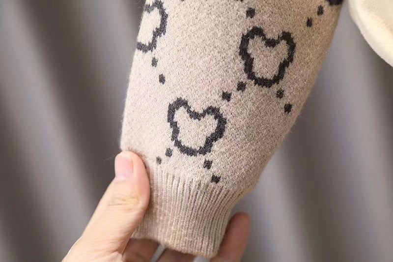 Beige arm sleeve with black heart patterns held by a hand against a neutral background