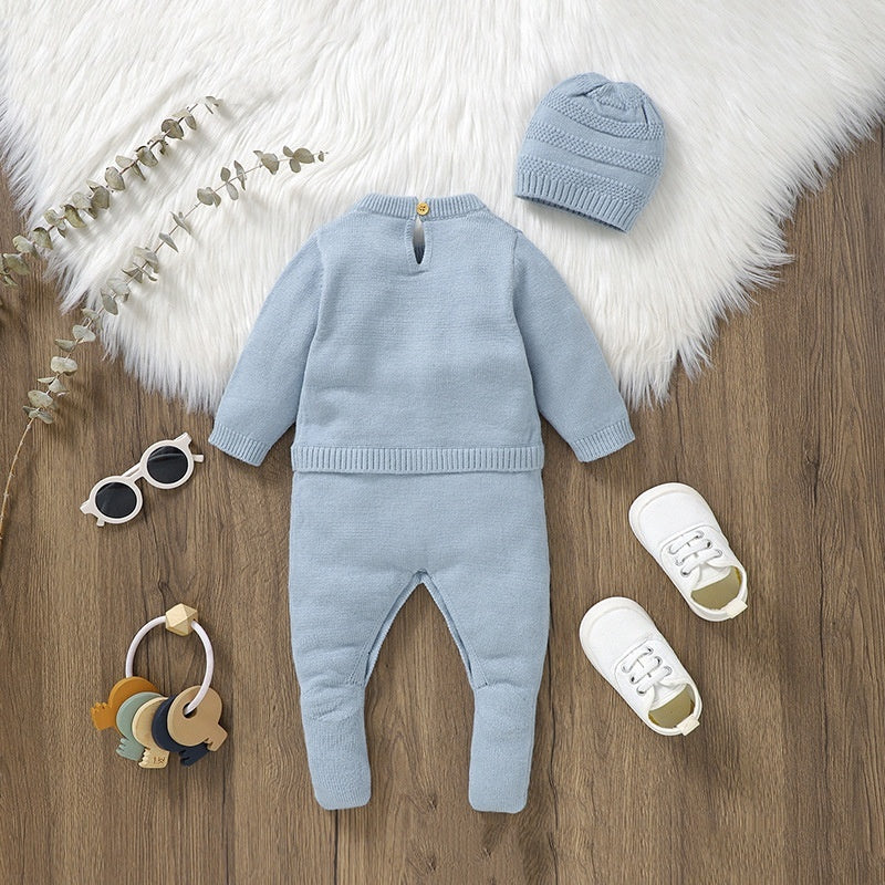 Baby blue outfit with hat, shoes, and toys on a wooden surface with white fur rug.
